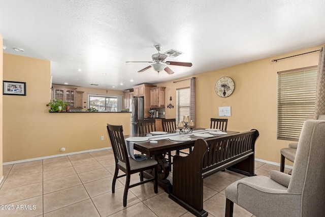 dining space featuring baseboards, visible vents, ceiling fan, a textured ceiling, and light tile patterned flooring