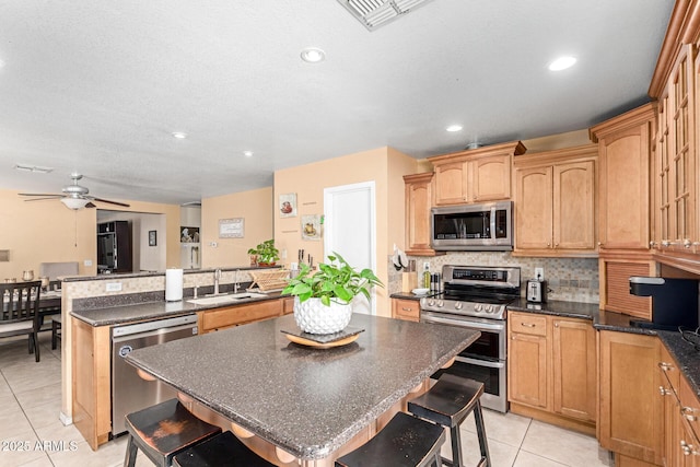 kitchen featuring a breakfast bar area, a sink, visible vents, appliances with stainless steel finishes, and decorative backsplash