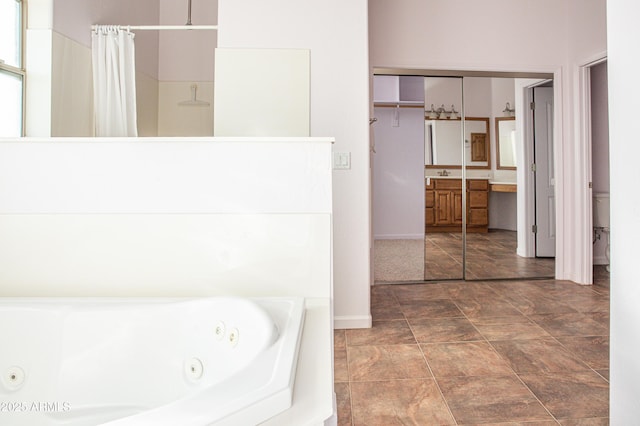 full bathroom with a whirlpool tub, curtained shower, toilet, and a sink