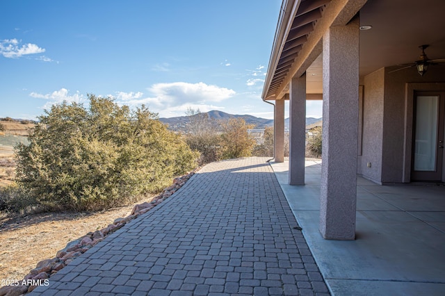 view of patio / terrace featuring a ceiling fan and a mountain view