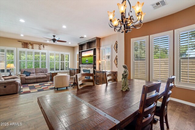 3350 S Holguin Way, Chandler, AZ 85248 - dining space featuring wood-type flooring, a stone fireplace, a chandelier, recessed lighting, and a ceiling fan
