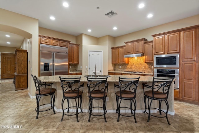 3350 S Holguin Way, Chandler, AZ 85248 - kitchen featuring built in appliances, under cabinet range hood, a large island with sink, a sink, and tasteful backsplash
