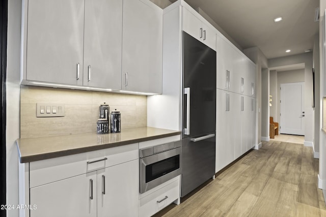 kitchen featuring white cabinets, decorative backsplash, light hardwood / wood-style floors, and high end black refrigerator