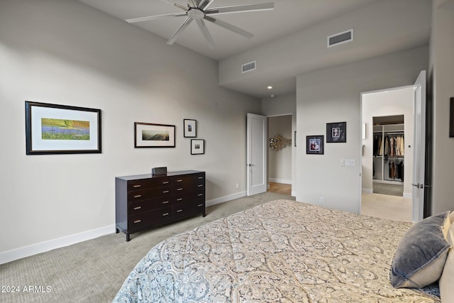 bedroom with a closet, a spacious closet, ceiling fan, and light colored carpet