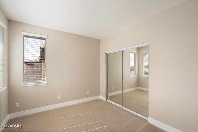 unfurnished bedroom featuring carpet floors, a closet, and baseboards