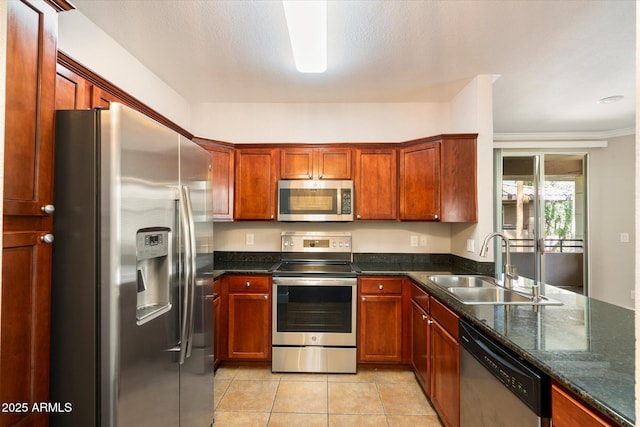 kitchen with stainless steel appliances, dark stone counters, a sink, and light tile patterned floors