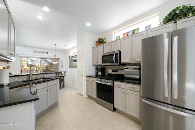 kitchen featuring decorative light fixtures, sink, white cabinets, dark stone counters, and stainless steel appliances