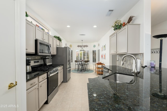 kitchen featuring sink, dark stone countertops, pendant lighting, stainless steel appliances, and decorative backsplash