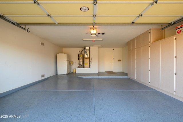 garage featuring water heater, white fridge, and a garage door opener