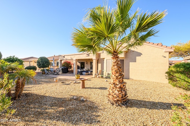 back of property with an outdoor living space and a patio area