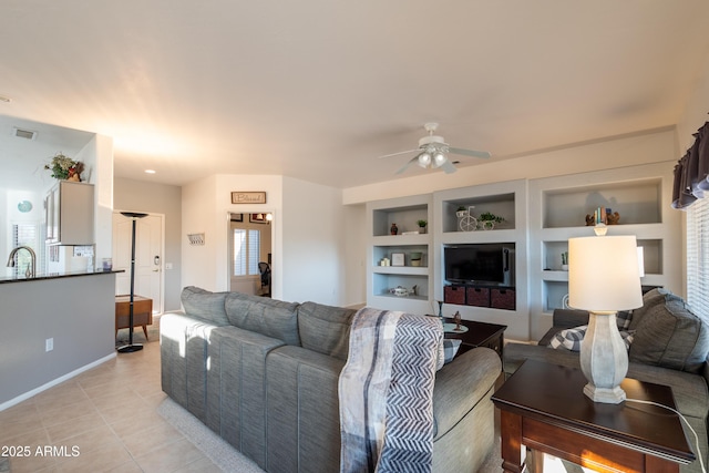 living room with sink, built in features, ceiling fan, and light tile patterned flooring