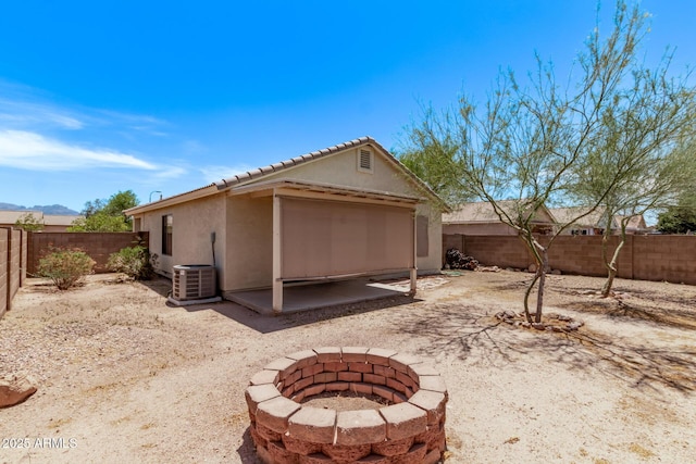 330 S Valley Dr, Apache Junction, AZ 85120 - rear view of house with a patio, a fenced backyard, stucco siding, an outdoor fire pit, and cooling unit