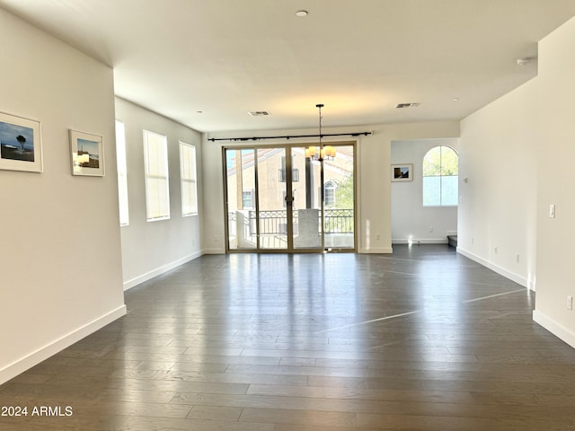 empty room featuring an inviting chandelier and dark hardwood / wood-style flooring