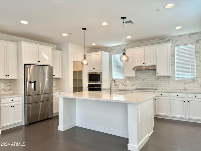 kitchen with a center island with sink, stainless steel appliances, dark hardwood / wood-style floors, and decorative light fixtures