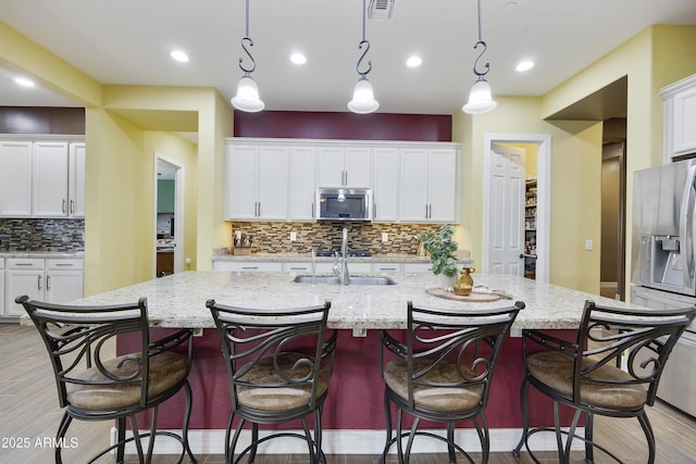 kitchen with appliances with stainless steel finishes, white cabinets, visible vents, and a sink