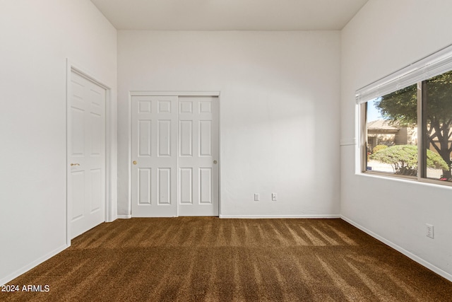 unfurnished bedroom featuring dark carpet and a closet