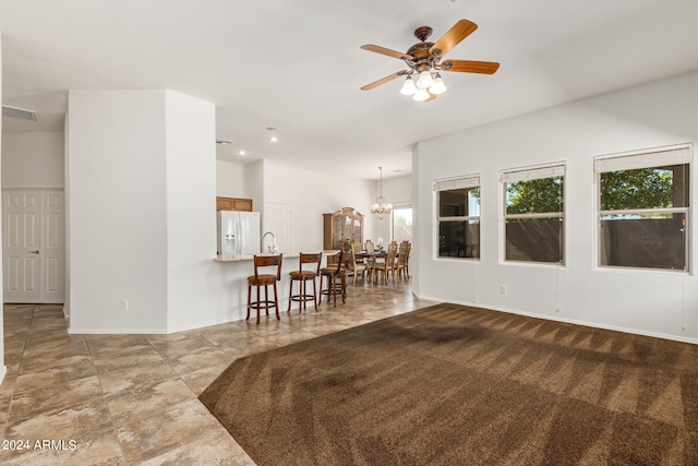 interior space with ceiling fan with notable chandelier and light colored carpet