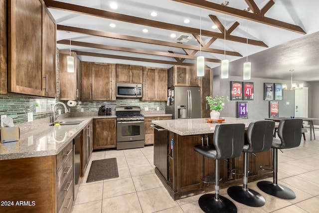 kitchen featuring appliances with stainless steel finishes, a kitchen island, decorative light fixtures, vaulted ceiling with beams, and sink