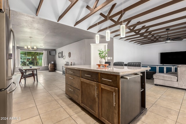 kitchen with light tile patterned floors, hanging light fixtures, stainless steel fridge, and a kitchen island