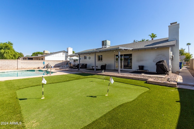 rear view of house featuring central AC unit, a fenced in pool, and a patio