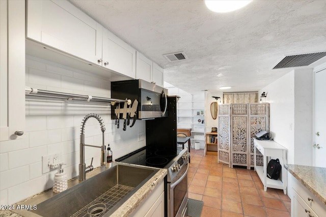 kitchen featuring light stone counters, white cabinets, sink, a textured ceiling, and stainless steel appliances