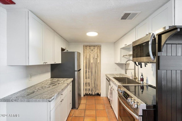 kitchen with appliances with stainless steel finishes, backsplash, sink, and white cabinets