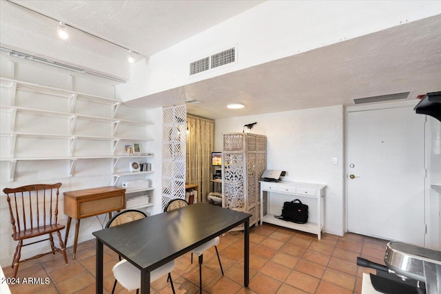 tiled dining area with a textured ceiling and rail lighting