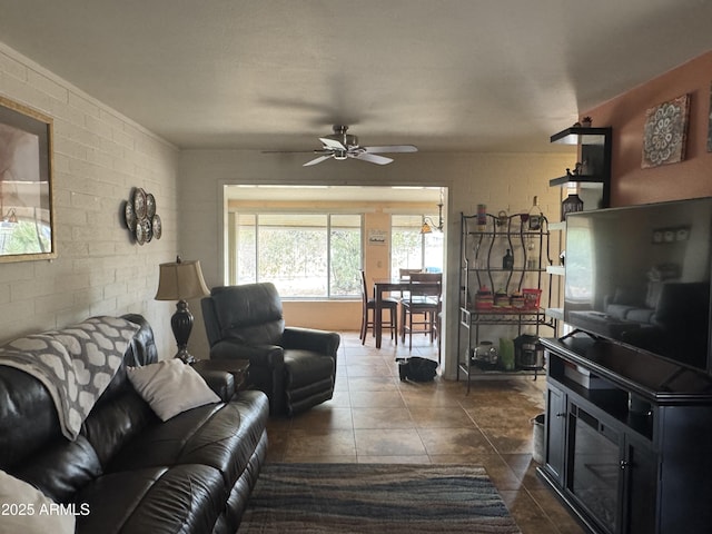 living room featuring brick wall, dark tile patterned floors, and a ceiling fan