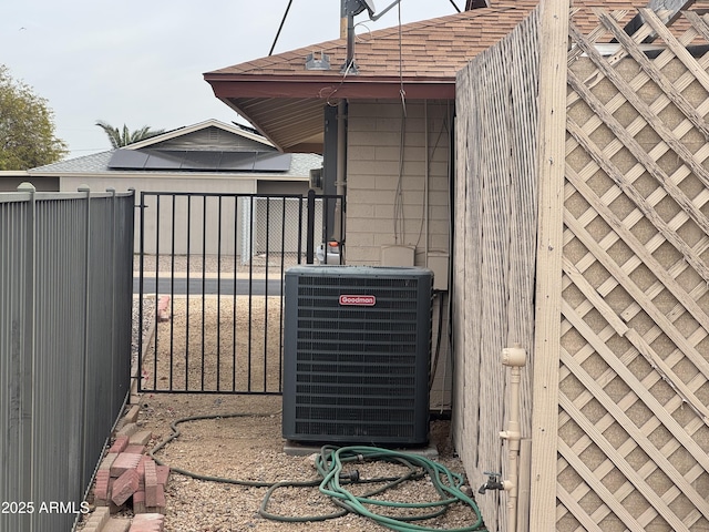 exterior details with a shingled roof, fence, a gate, and central air condition unit