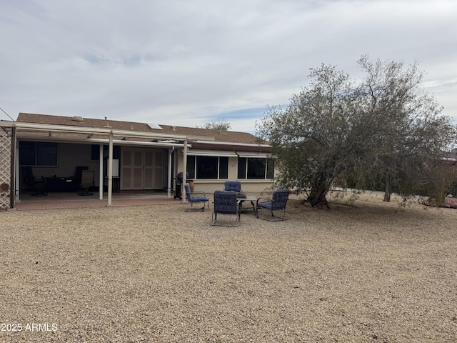 rear view of house with a patio area and roof with shingles