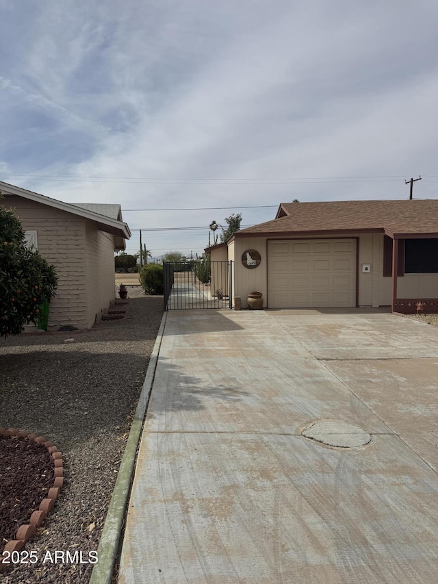 view of home's exterior with a garage, a shingled roof, a gate, and concrete driveway