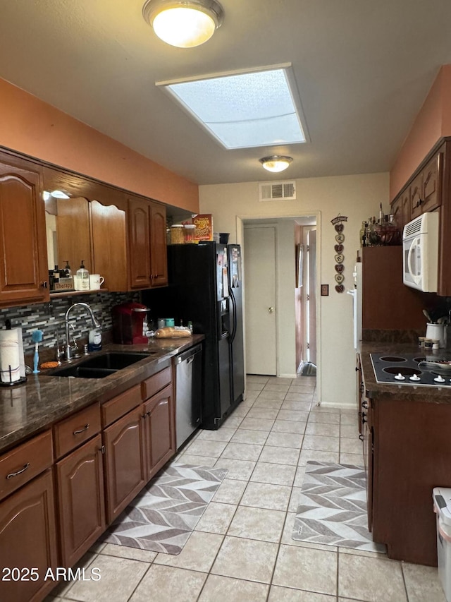 kitchen with visible vents, dishwasher, white microwave, stovetop, and a sink