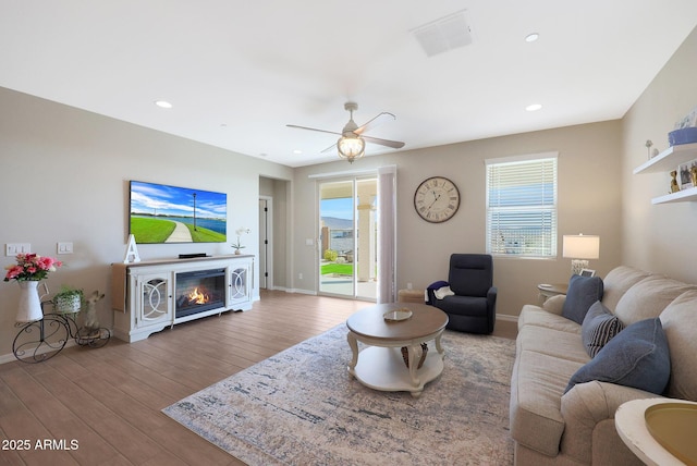 living room with wood-type flooring, a wealth of natural light, and ceiling fan