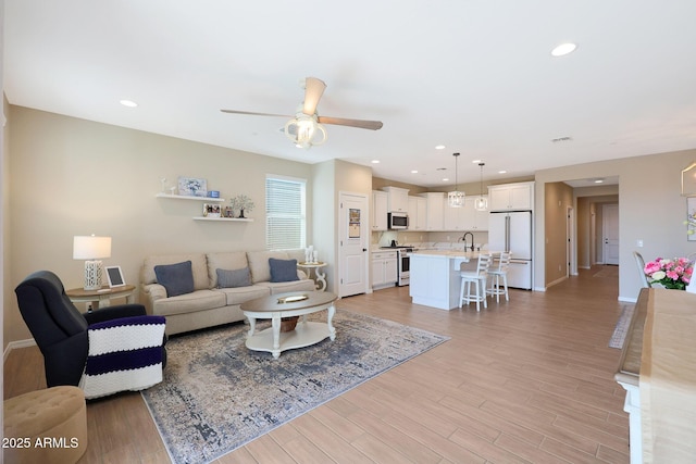 living room with sink, ceiling fan, and light hardwood / wood-style flooring