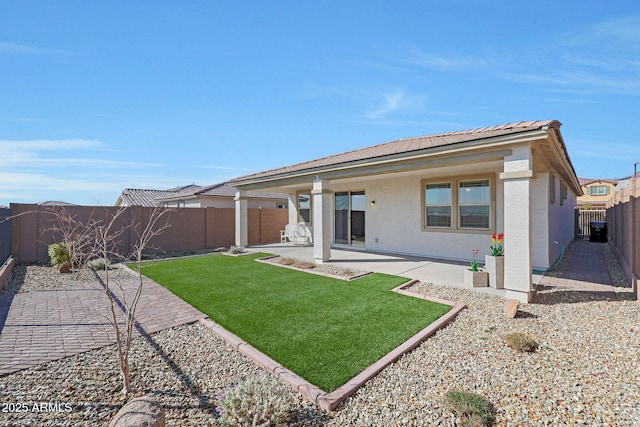 rear view of house featuring a lawn and a patio