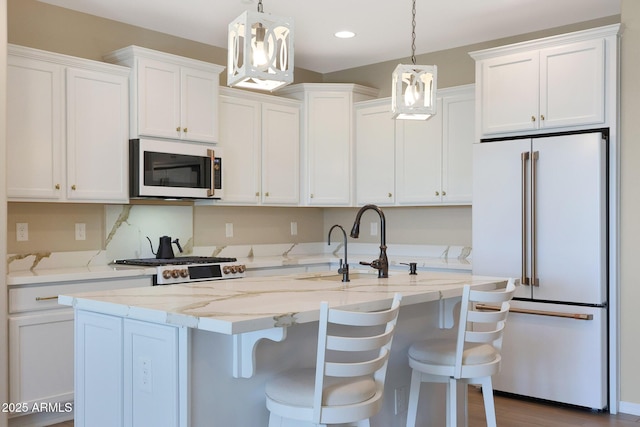 kitchen with pendant lighting, white appliances, a breakfast bar, white cabinetry, and a kitchen island with sink