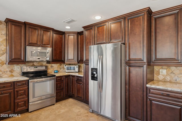 kitchen with stainless steel appliances, light tile patterned floors, backsplash, and light stone counters