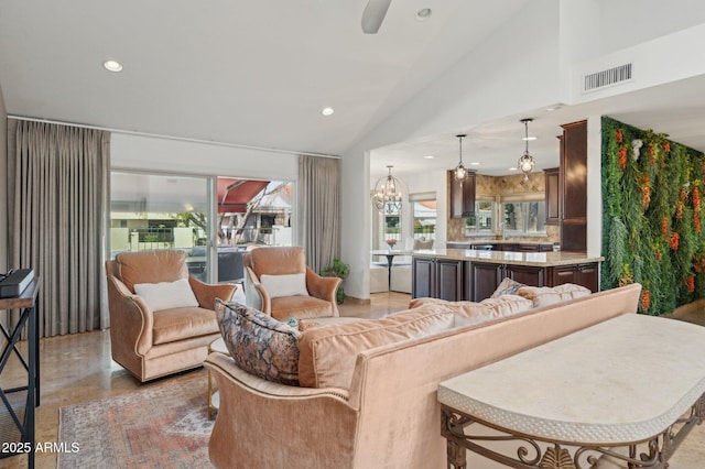 living room featuring high vaulted ceiling and ceiling fan with notable chandelier