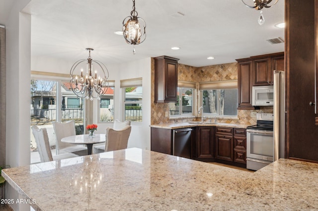 kitchen featuring decorative light fixtures, sink, dark brown cabinetry, stainless steel appliances, and an inviting chandelier