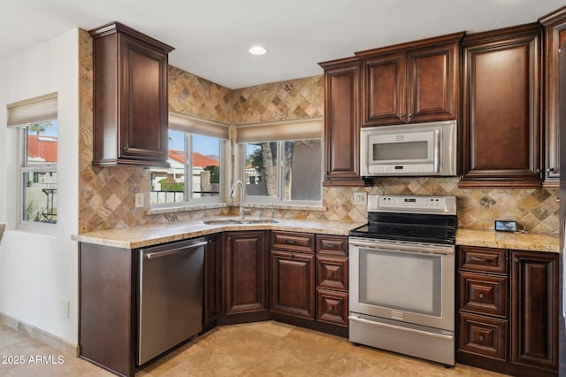 kitchen with sink, appliances with stainless steel finishes, backsplash, plenty of natural light, and light stone counters