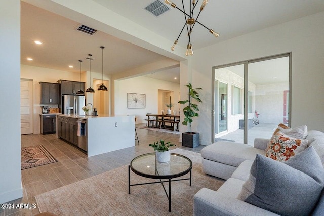 living room featuring an inviting chandelier, sink, and light wood-type flooring