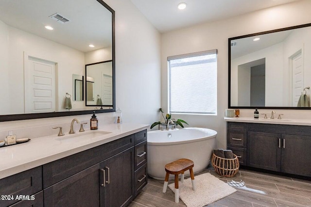 bathroom with vanity, a washtub, and hardwood / wood-style flooring