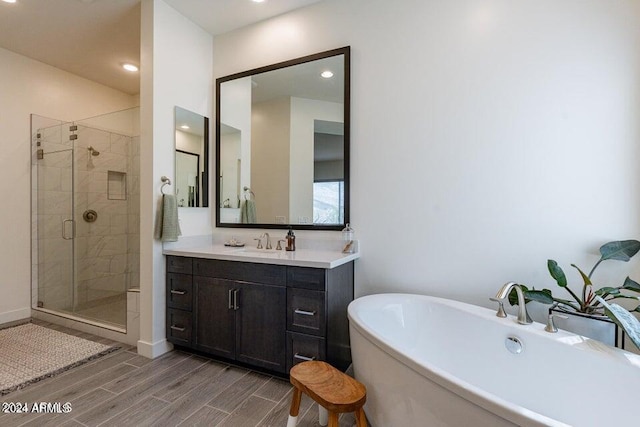 bathroom with wood-type flooring, vanity, and independent shower and bath