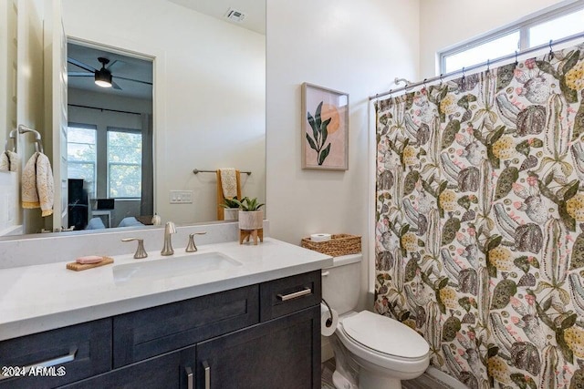 bathroom featuring curtained shower, ceiling fan, vanity, and toilet