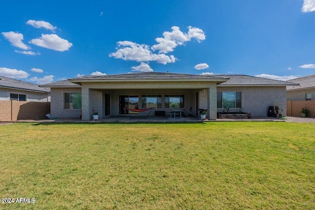 rear view of house with a patio and a lawn