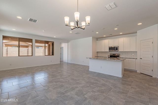 24184 W Gibson Ln, Buckeye, AZ 85326 - kitchen featuring appliances with stainless steel finishes, open floor plan, recessed lighting, backsplash, and a chandelier