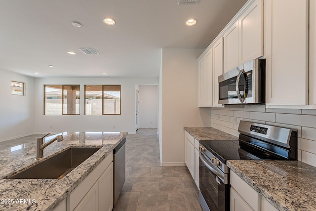 24184 W Gibson Ln, Buckeye, AZ 85326 - kitchen with stainless steel appliances, tasteful backsplash, recessed lighting, white cabinets, and light stone countertops