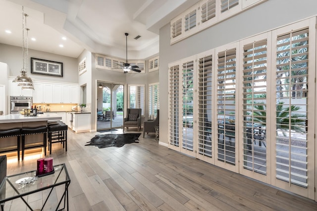 living room featuring visible vents, a towering ceiling, recessed lighting, light wood finished floors, and ceiling fan