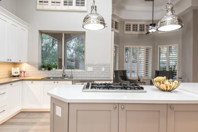 kitchen with decorative backsplash, stainless steel gas stovetop, pendant lighting, and a sink