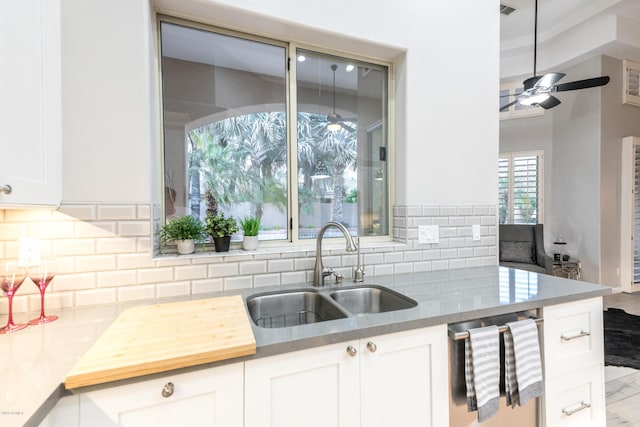 kitchen featuring backsplash, ceiling fan, dishwasher, white cabinets, and a sink